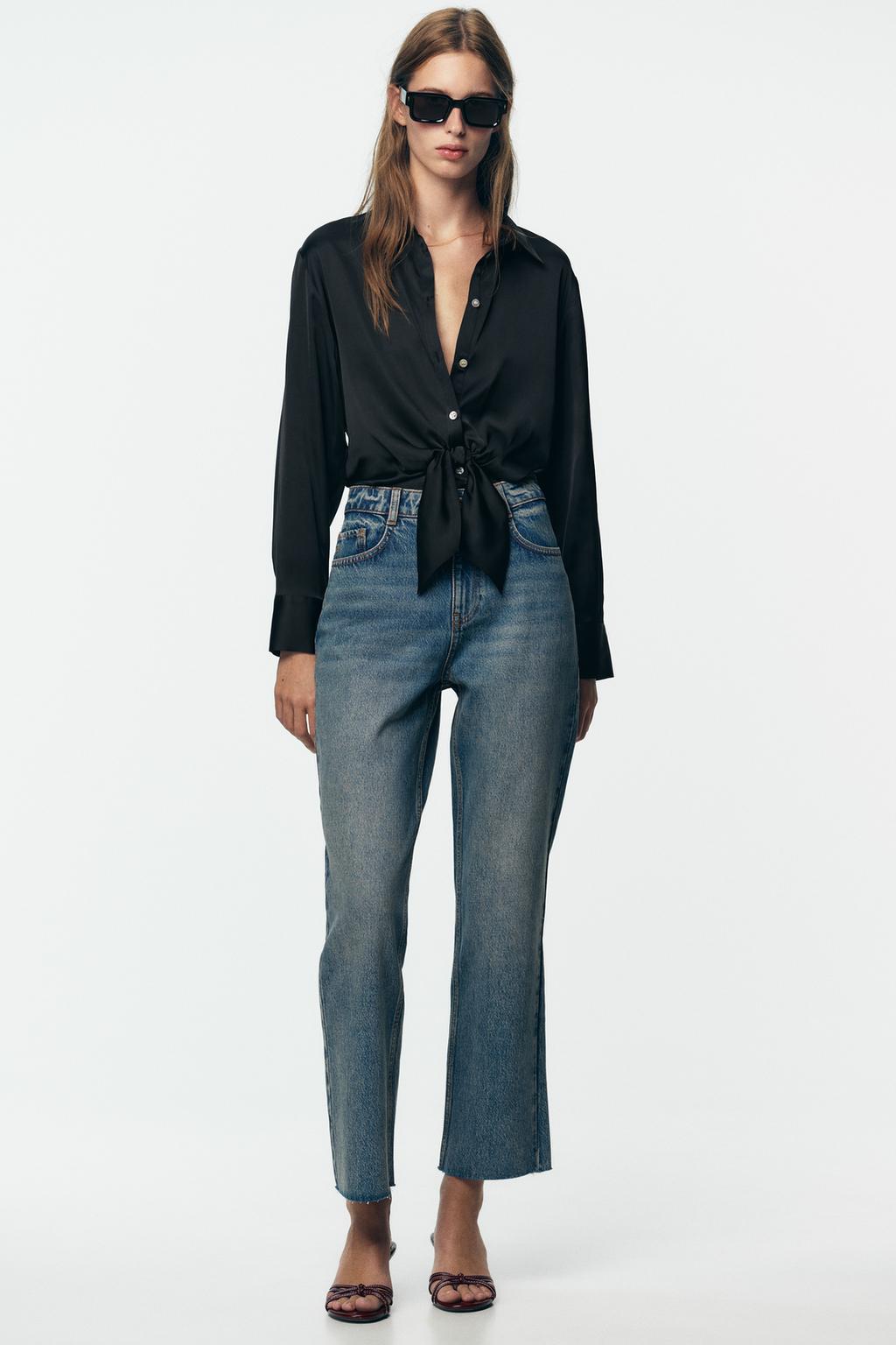 Set of a knotted black blouse and high-waisted blue jeans with straight legs and side pockets.
