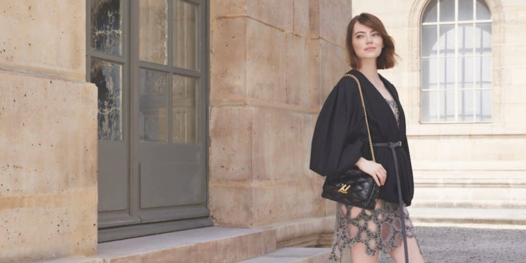 Emma Stone wearing Louis Vuitton in the Fall 2025 campaign, styled in a retro-inspired black outfit with luxury handbag.