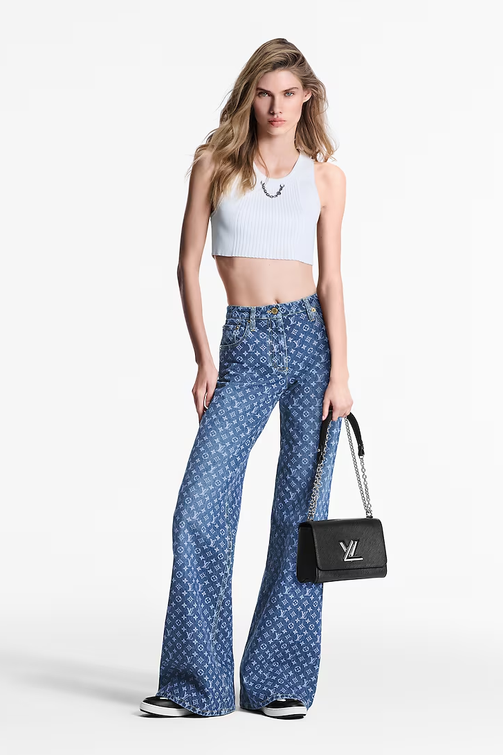 Model wearing short tee with a black bag and Louis Vuitton monogram flared jeans