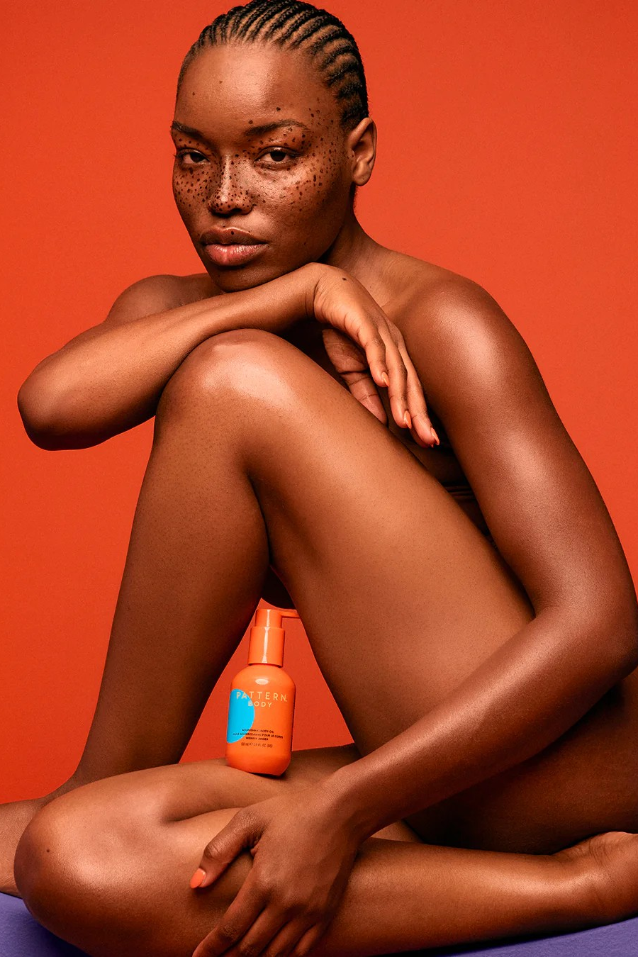 Model Holding Pattern Nourishing Body Oil with Orange Background Brand by Tracee Ellis Ross